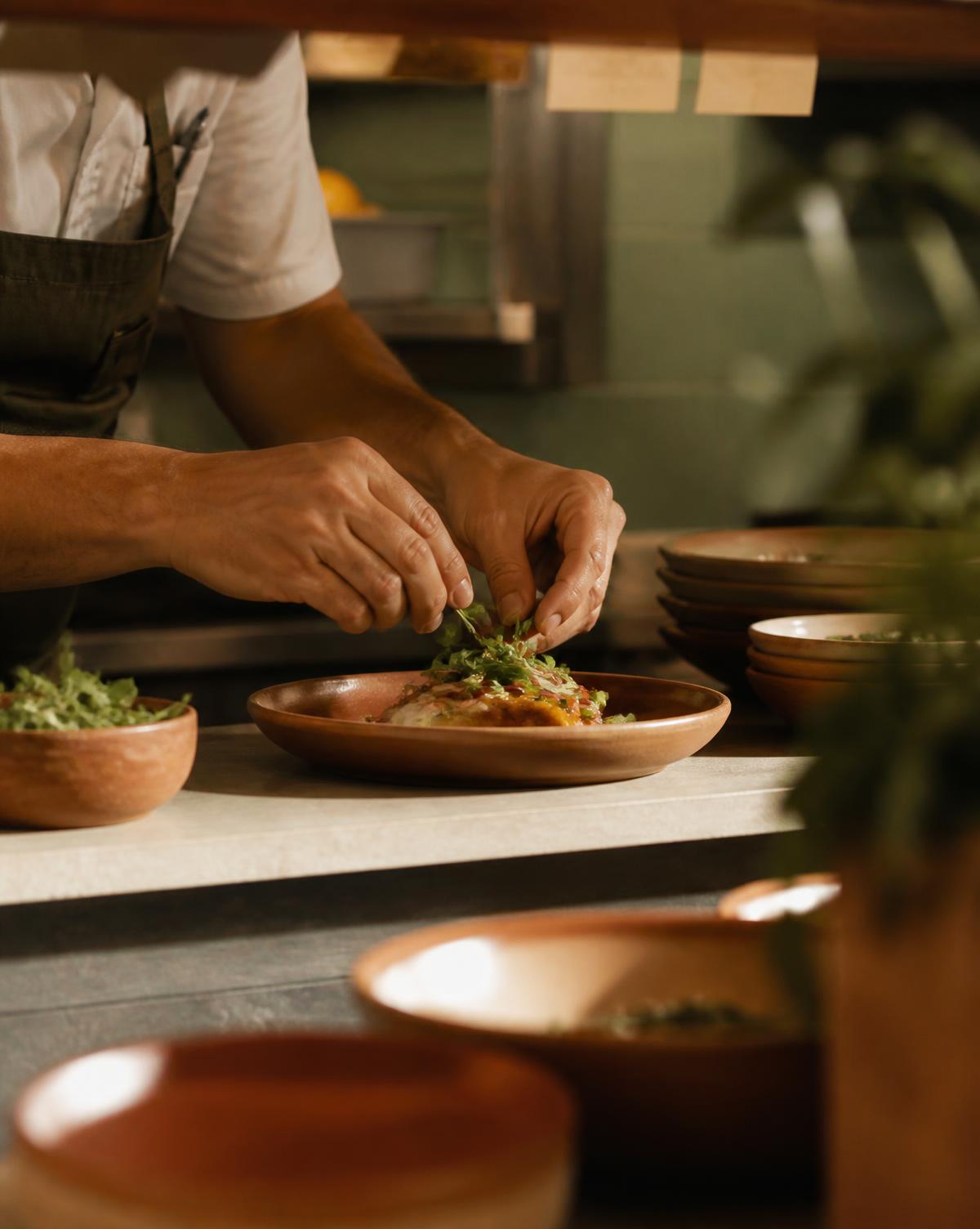 A chef finishing a plate at the pass