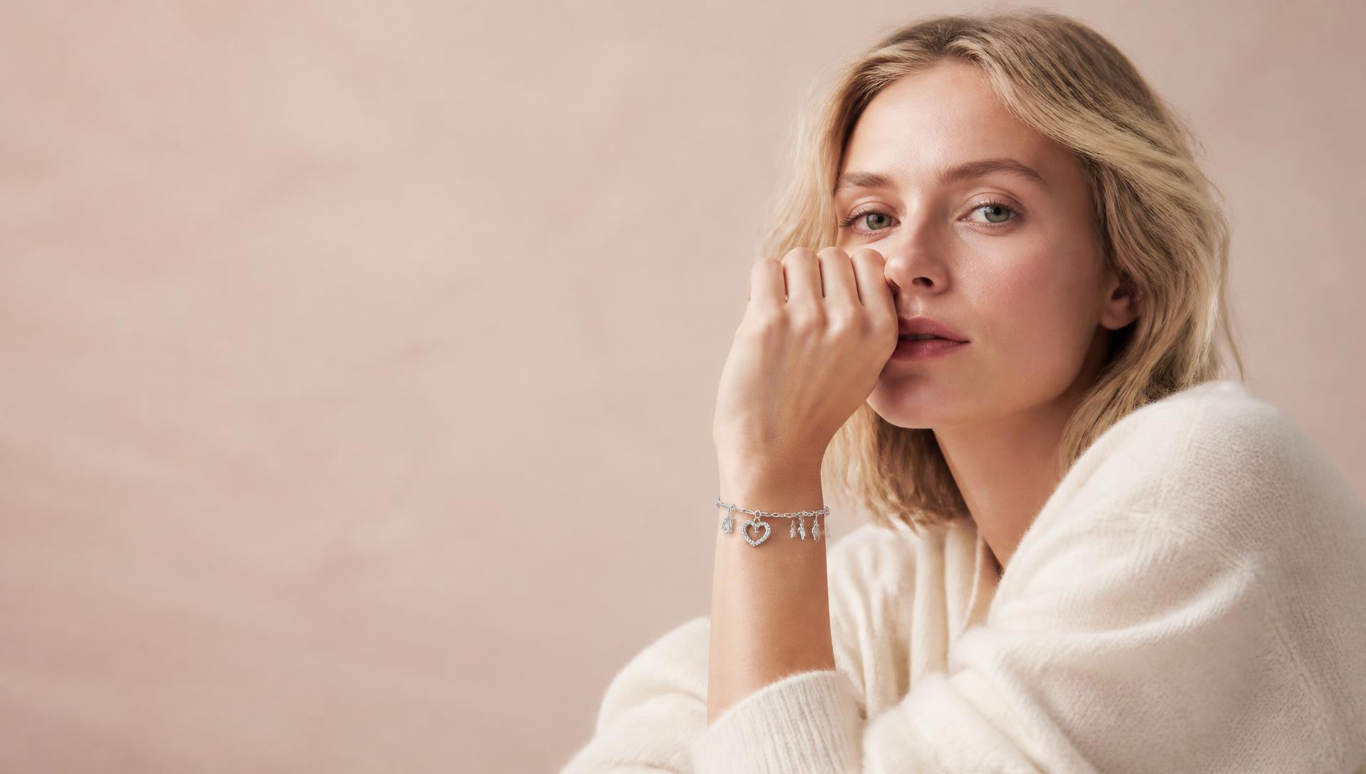 Model in cream knitwear wearing a sterling silver charm bracelet