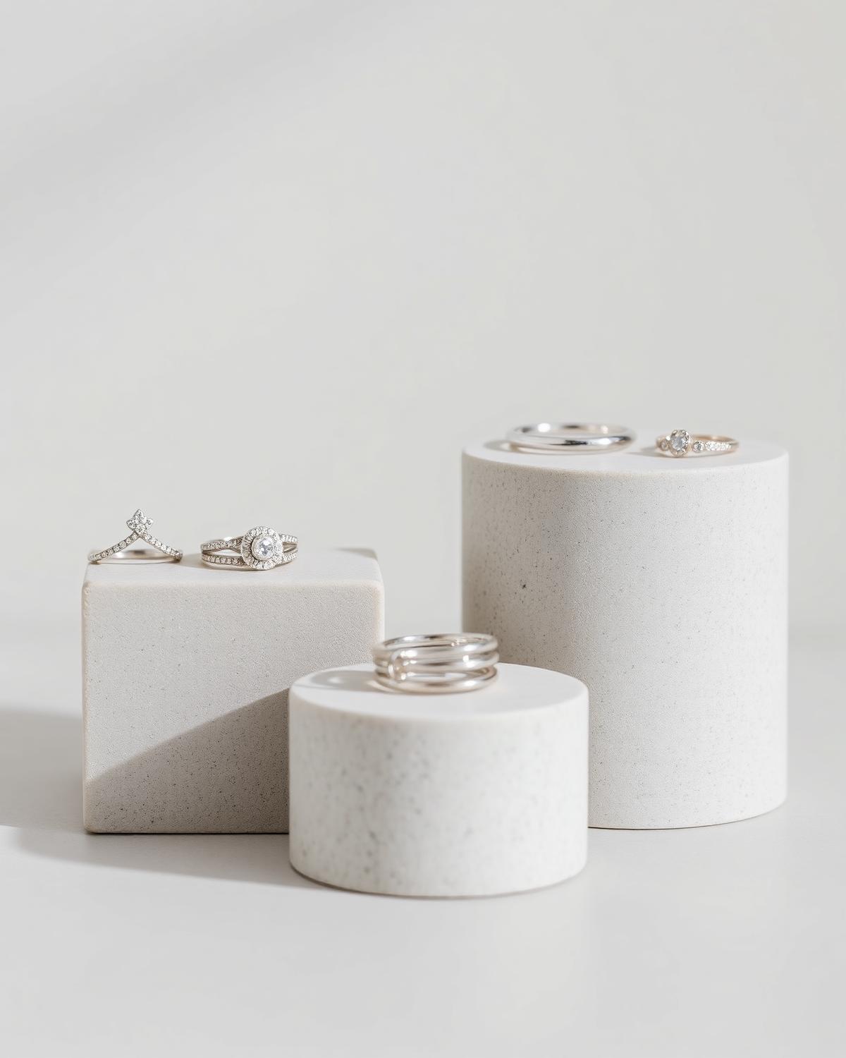 Silver rings displayed on stone plinths